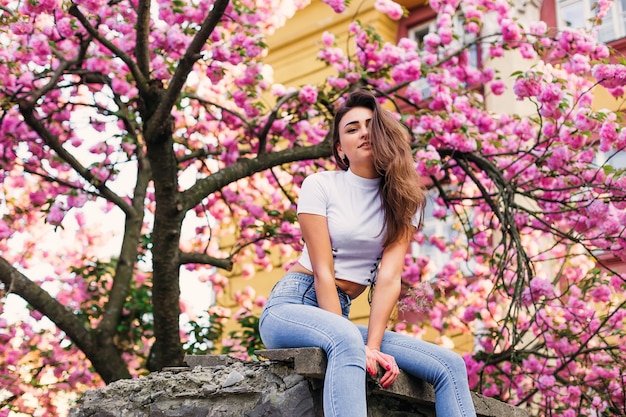 Garota posando com ramos de flores do lado de fora