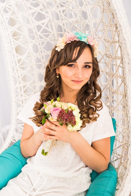 Garota posando em uma grinalda decorativa de flores artificiais e buquê dentro de casa
