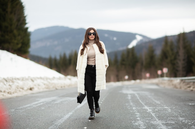 Garota posando na estrada na floresta de inverno.