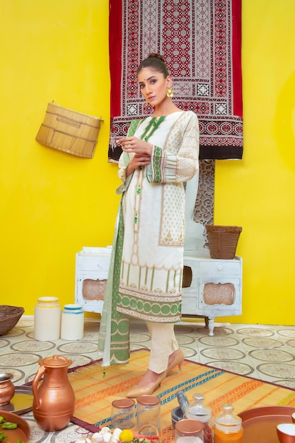 Garota posando para sessão de fotos tradicional em fundo amarelo vestindo Shalwar Kameez