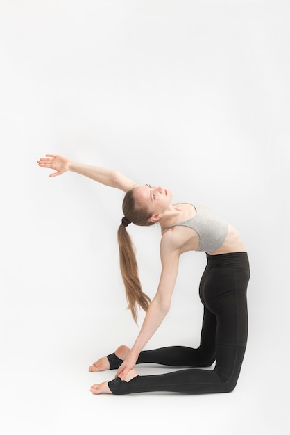 Garota pratica ioga em Camel Pose em fundo branco. Ustrasana. Instrutor de ioga jovem realiza asana.