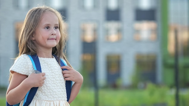 Garota pré-escolar tímida vai para a escola com expressão animada