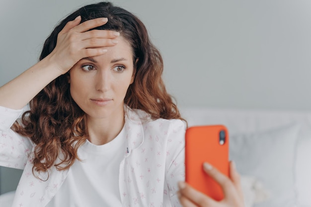 Garota preocupada está lendo notícias de problemas olhando para a tela do smartphone Ataque de estresse e ansiedade