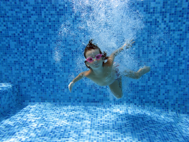 Garota pula e nada na piscina debaixo d'água