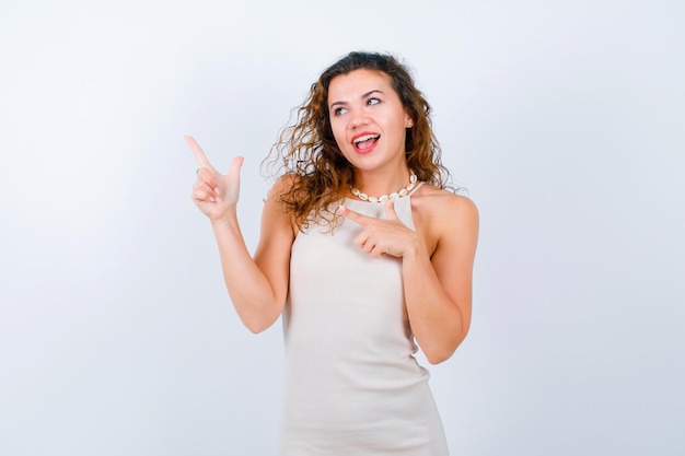 Garota rindo está olhando e apontando para cima com o dedo indicador no fundo branco