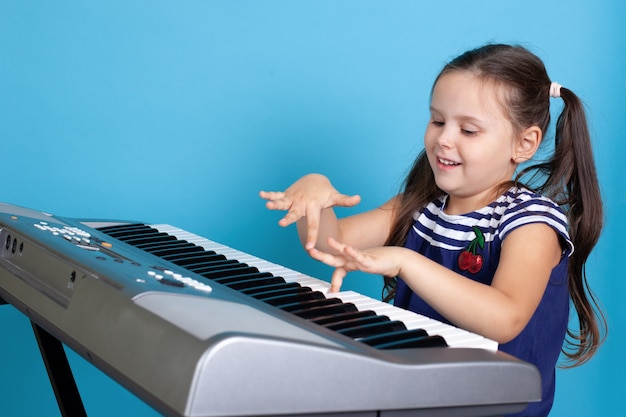 Garota rindo tocando uma melodia nas teclas de um sintetizador eletrônico