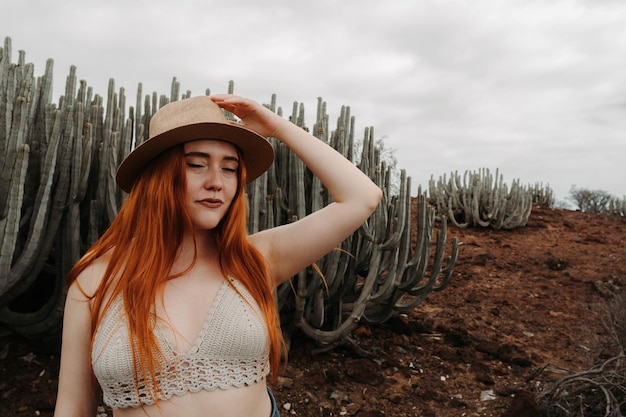 Garota ruiva colocando seu chapéu no deserto