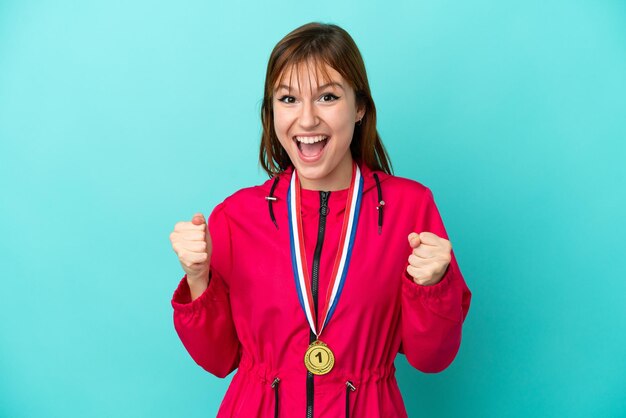 Garota ruiva com medalhas isoladas o fundo azul comemorando uma vitória na posição de vencedor