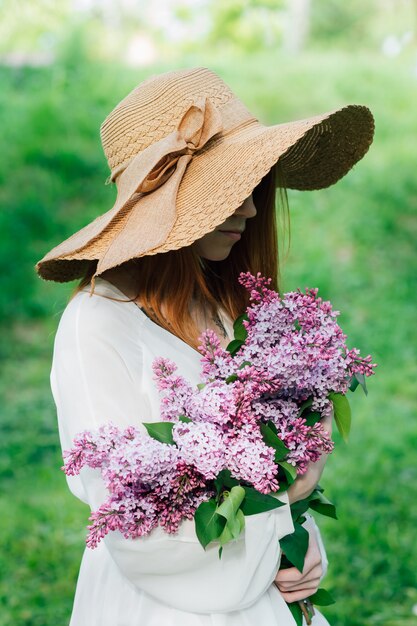 Garota ruiva com um buquê de lilases em um jardim de primavera