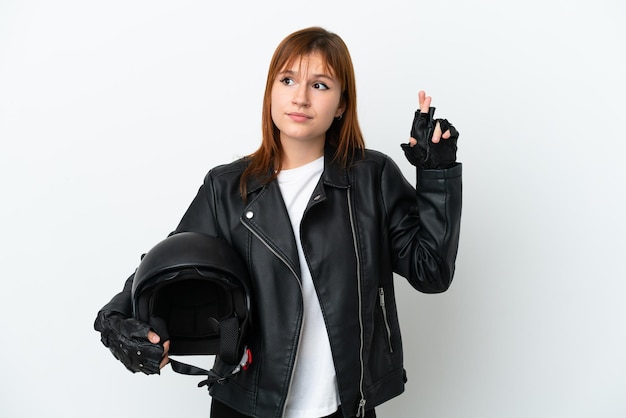 Garota ruiva com um capacete de moto isolado no fundo branco com dedos cruzando e desejando o melhor