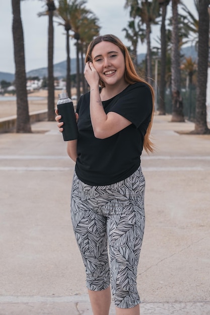 Foto garota ruiva desportiva com uma garrafa preta