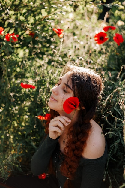 Foto garota ruiva em um campo de papoulas