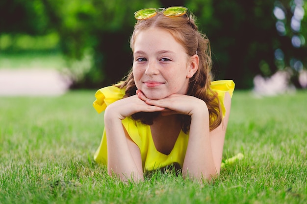 Garota ruiva em um vestido amarelo na grama do parque no verão. foto de alta qualidade