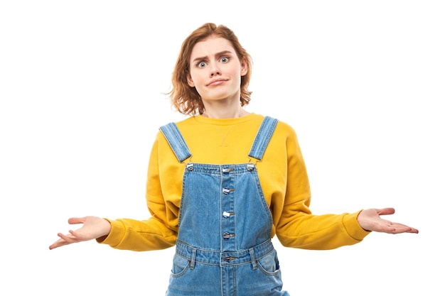 Garota ruiva inteligente em mãos casuais achando que as dúvidas tomam decisões isoladas no fundo branco do estúdio