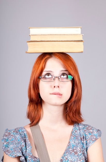 Garota ruiva manter livros na cabeça dela. Tiro do estúdio.