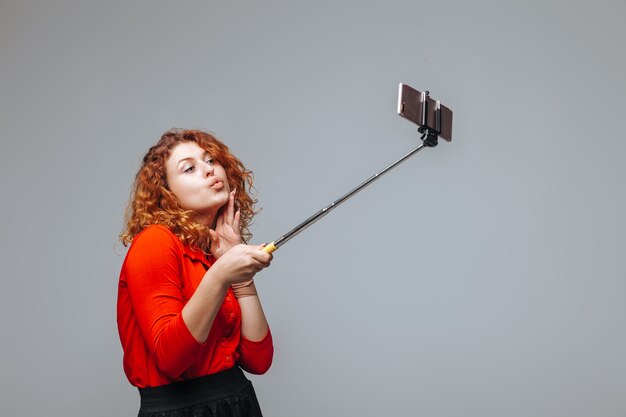 Garota ruiva tirando uma selfie no telefone no monopé