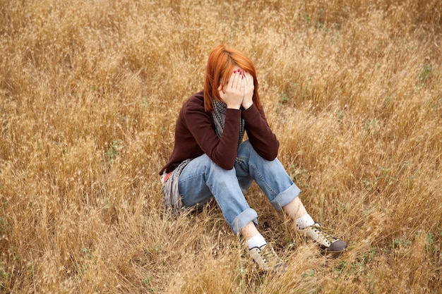 Garota ruiva triste e solitária no campo