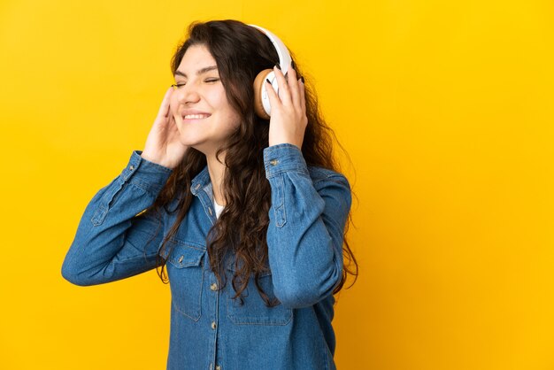 Garota russa adolescente isolada em um fundo amarelo ouvindo música e cantando