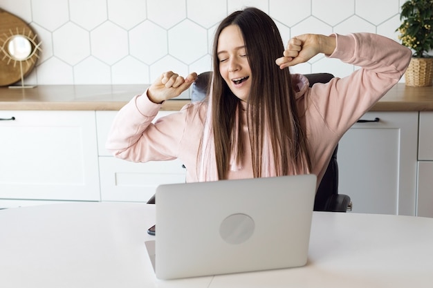 Garota se espreguiçando, cansada de trabalhar no computador