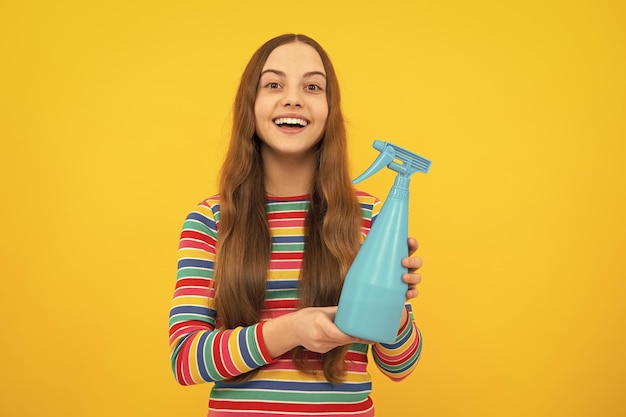 Garota segurando a garrafa de detergente Garoto feliz segura produto desinfetante em spray na garrafa para desinfecção de fundo amarelo de espaço de cópia