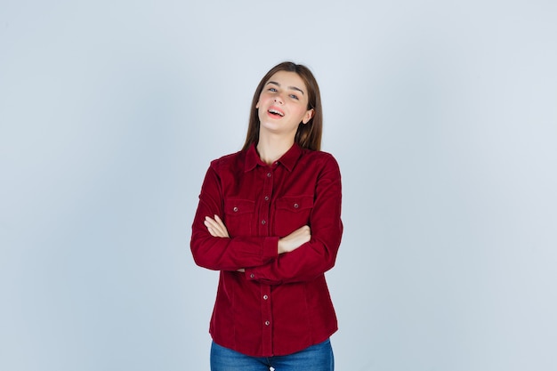 Garota segurando os braços cruzados em uma camisa casual e parecendo feliz