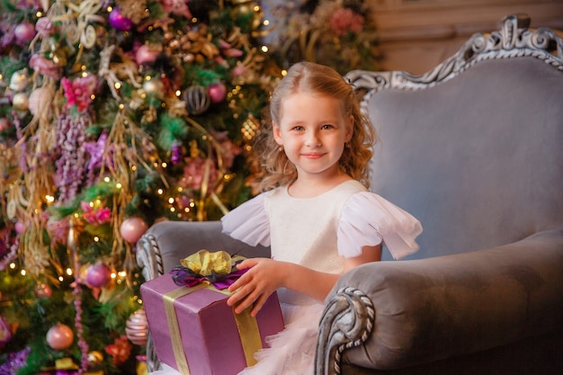 garota segurando um presente perto da árvore de Natal