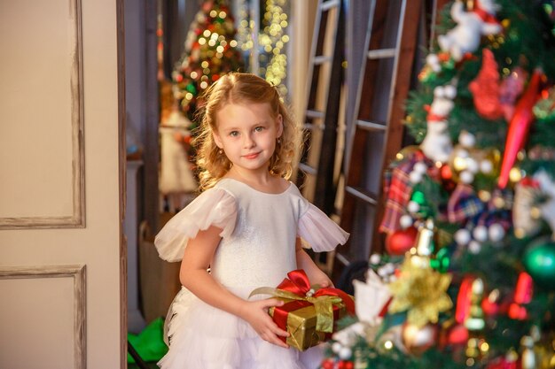 garota segurando um presente perto da árvore de Natal