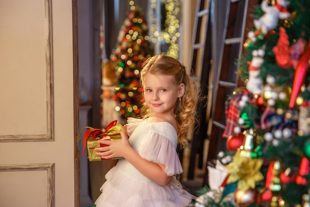 garota segurando um presente perto da árvore de Natal