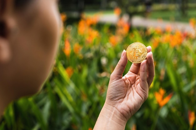 Garota segurando uma moeda Bitcoin dourada no parque Moeda de criptomoeda Mercado financeiro