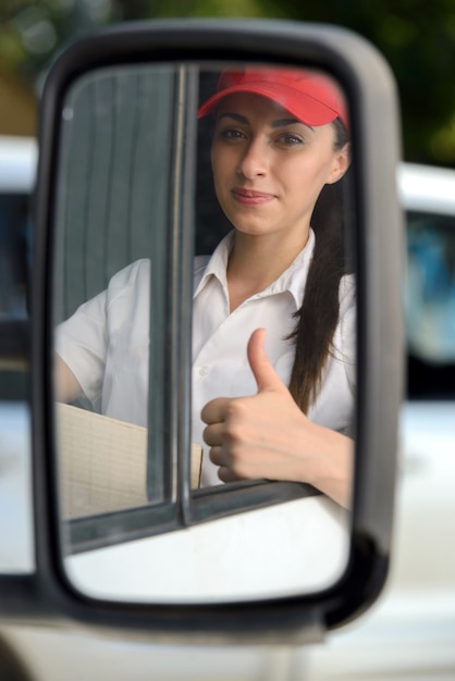 Garota senta-se ao volante e mostra polegares para cima.