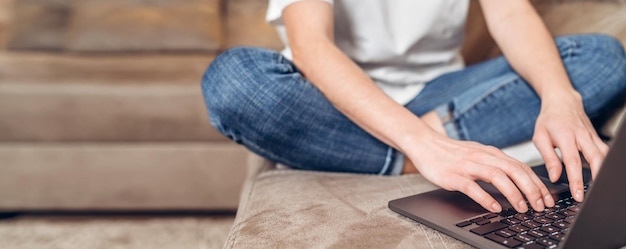 Garota sentada em casa trabalhando e navegando online no laptop