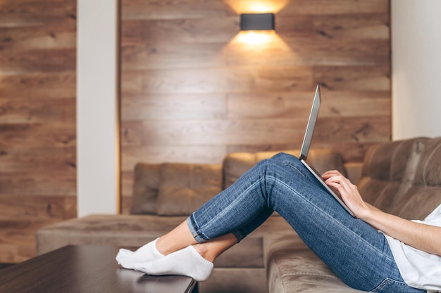 Garota sentada em casa trabalhando e navegando online no laptop