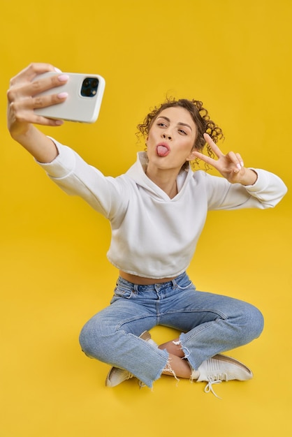 Garota sentada em pose de lótus tirando selfie