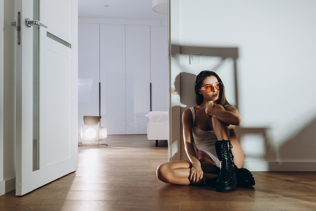 Foto garota sexy em uma camiseta branca posando no chão da cozinha