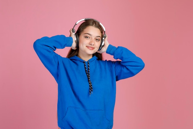 Foto garota sonhadora sorridente curtindo a música favorita enquanto pressiona o fone de ouvido nos ouvidos com os cotovelos separados