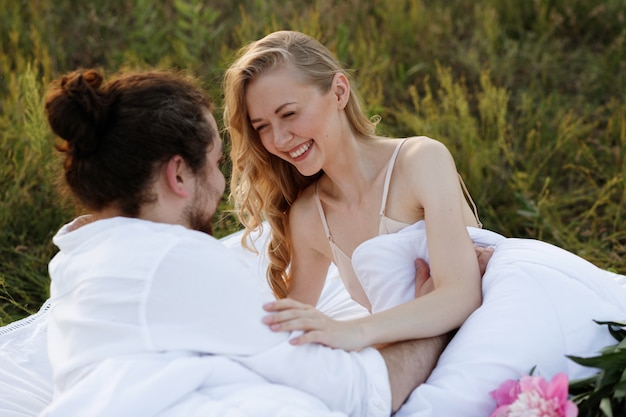 Garota sorri alegremente para o cara. casal na cama de manhã ao ar livre. Bom Dia