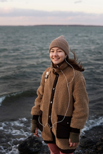 Foto garota sorridente em foto média à beira-mar