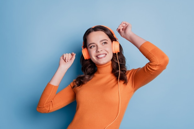 Foto garota sorridente muito legal ouvindo música em fones de ouvido sobre fundo azul