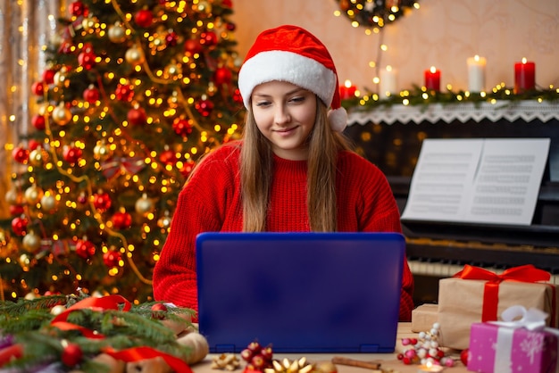 Garota sorridente trabalhando no computador decorado para o conceito de celebração de Natal da sala de estar de Natal