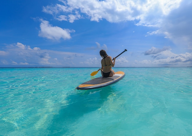 Garota surfista de SUP nas Maldivas