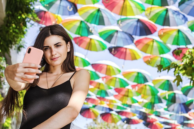 Garota tira uma selfie em um fundo de guarda-chuvas coloridos Retrato