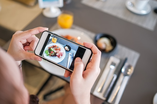 Garota tirando foto de comida com a câmera do telefone