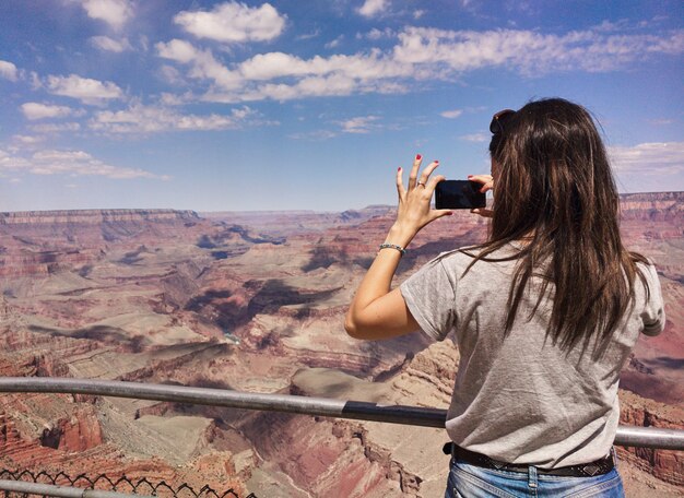 Garota tirando fotos no Grand Canyon com telefone móvel.