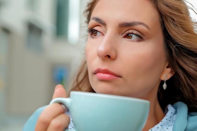 Garota tomando café na rua uma xícara de café uma xícara de café e o rosto de uma garota closeup