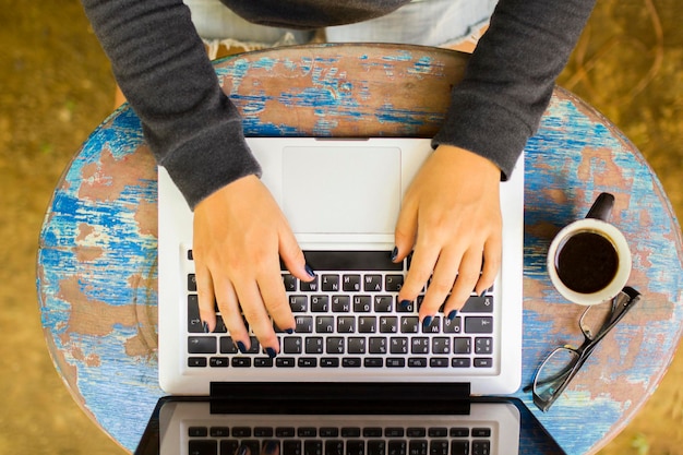 Garota trabalhando com laptop em uma mesa de madeira vintage