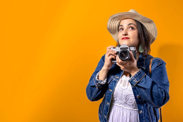 Garota turista tirando fotos com seu conceito de viagem de câmera retrô fundo laranja