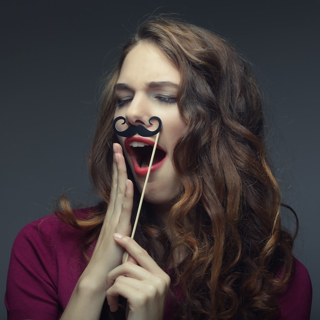 Garota usando bigodes falsos.