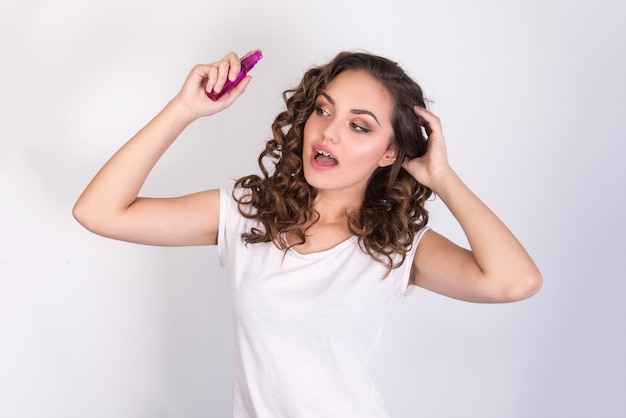 Foto garota usando um produto para o cabelo para cabelos cacheados em fundo branco