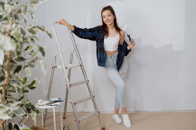 Garota vestida com camisa de roupas apertadas passa tempo no novo apartamento durante o acabamento da renovação