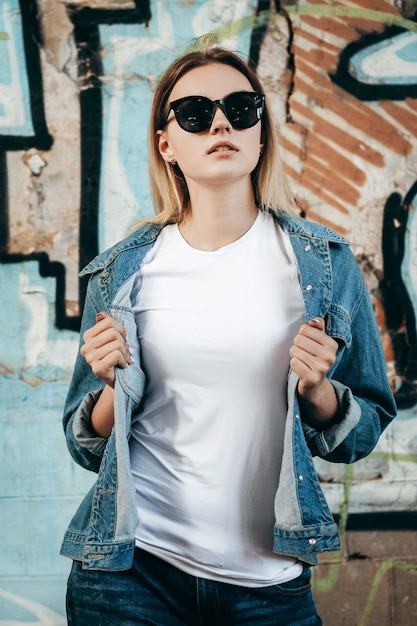 Garota vestindo camiseta e jaqueta de algodão posando contra a rua